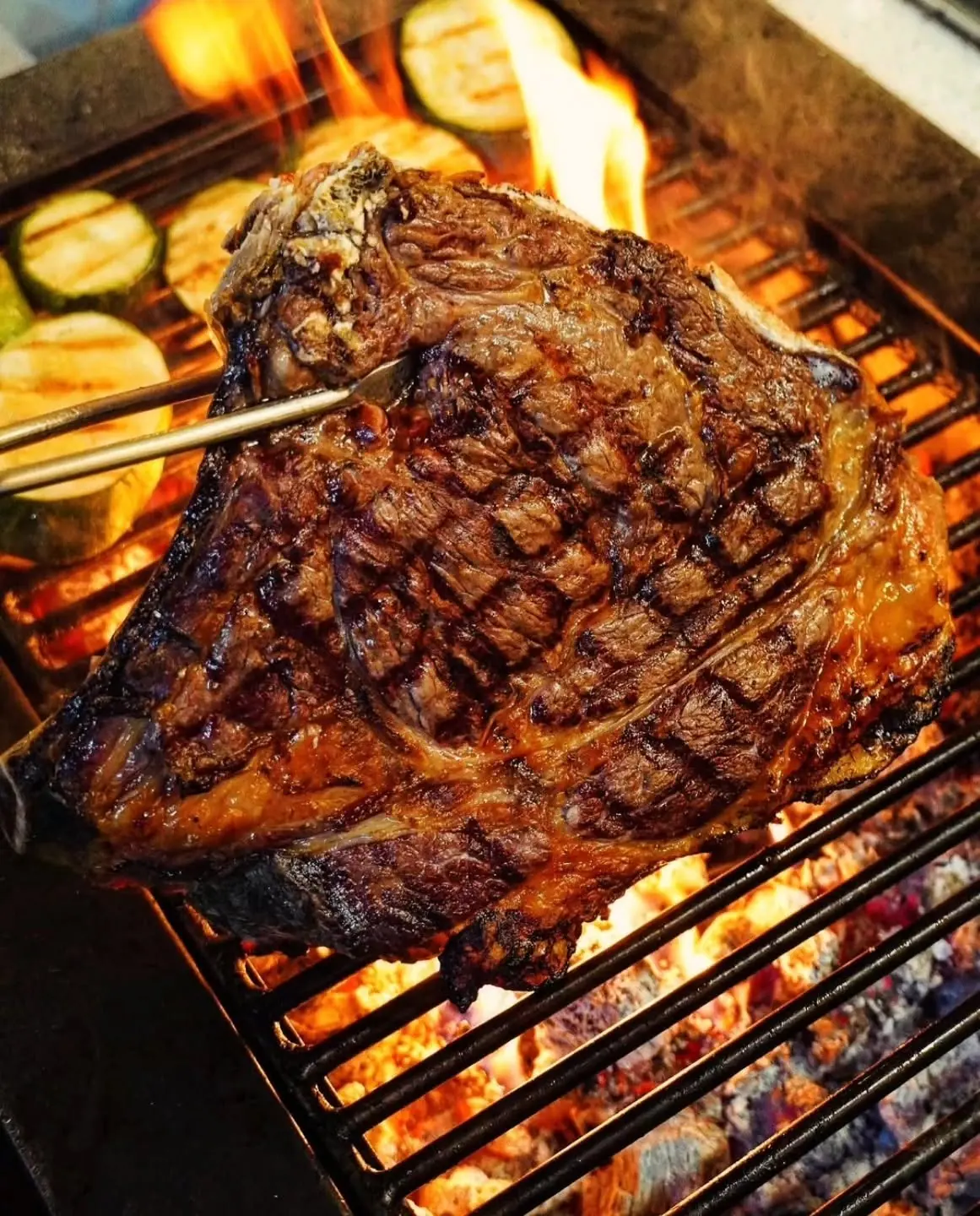 Rib steak cooking over the charcoal grill