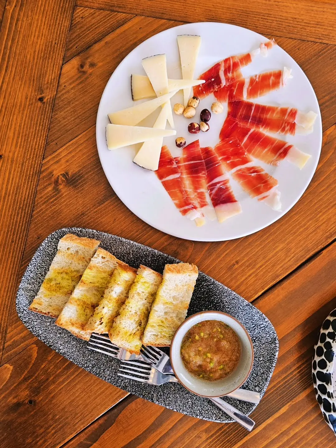 Jamón, queso y pan para compartir en una mesa de Carbón Carbón
